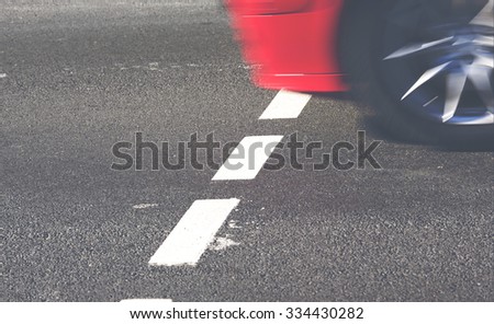 A car is driving through the pedestrian way. This image shows how fast the car is actually moving even in slow speed. Image has a vintage effect applied.
