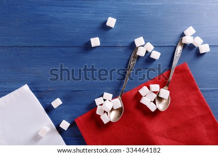 Creative musical notes made of spoon and sugar with red cotton napkin on blue wooden background