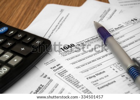 Tax form with pen and calculator on the wooden desk. Business concept