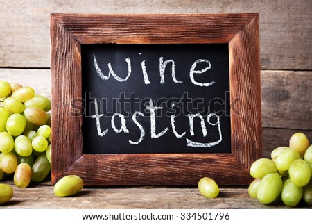 old square chalk scripted frame with grape on wooden background