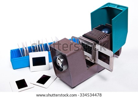 Retro cine-projector on the white background. Vintage filmstrip projector on the white background. Slides in blue box and some slides on white background .