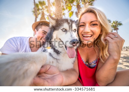 Happy couple taking a selfie with their husky - Dog holding camera and taking a funny picture with his family