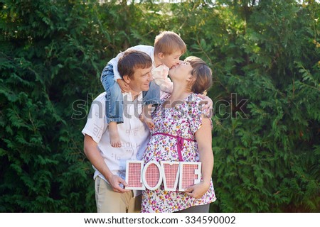 Family of mother father and boy, little boy kissing his mom and parents takes letters LOVE.