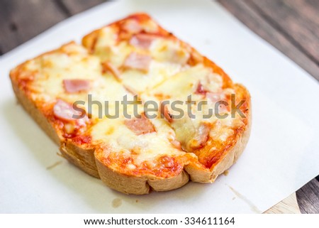 Bread baked with pizza sauce and cheese on white paper cooking.