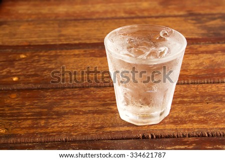 glass of clear alcohol on wooden table