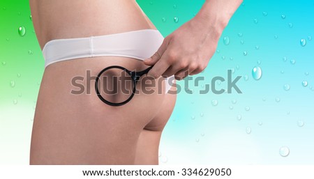 Woman checking cellulite with magnifying glass on the aquamarine background