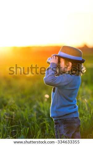 Little boy with a camera in the field