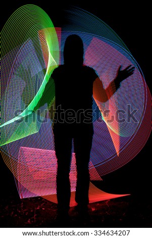Man silhouette on colorful background made with light painting or light drawing photographic technique. Light drawing photo made by moving lights during long exposure
