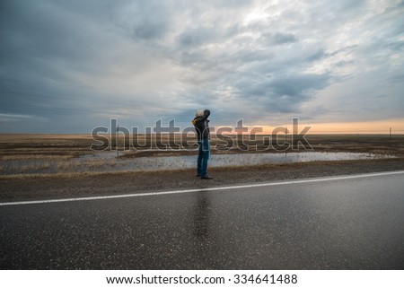 warm spring-like wearing man's photographer back across the road and photographs autumn landscape  water marshland under dramatic sky with power line at morning