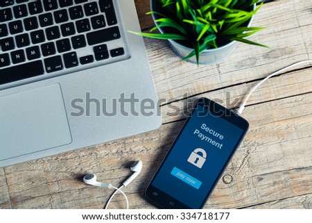 Secure Payment notification in a smart phone screen. Close up view of wooden business desk