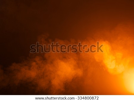 Yellow/Orange mysterious fog photographed on a black background. Ideas as a background texture or overlay. Bright light coming from the bottom right of the image.  Royalty-Free Stock Photo #334800872