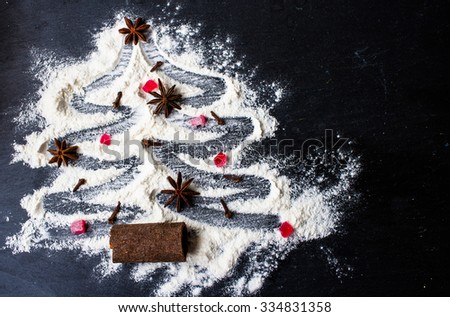 Christmas tree made from flour on a black background with anise stars and cinnamon sticks