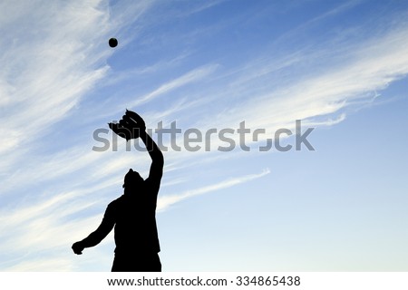 A man silhouetted by the sunset is just beginning catch ball with glove