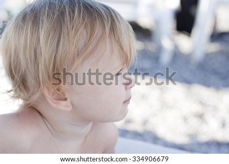 Profile closeup portrait of small pensive sweet toddler girl with long eyelashes round cheeks blonde hair and cute face, horizontal picture. Charming european cool looking girl. Colorful photo.