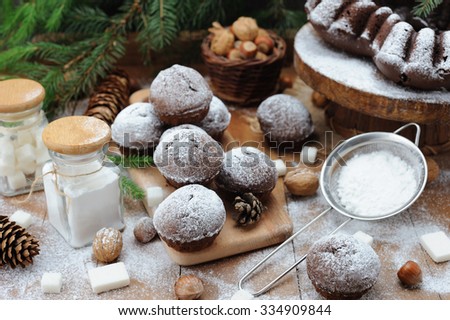 Chocolate muffin and cupcakes with holiday decorations on a rustic wood background