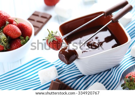 Chocolate fondue with fresh berries on a blue wooden table
