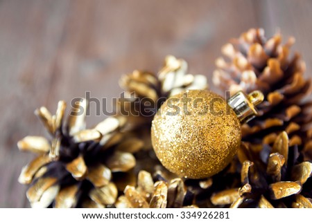 Golden cones and Christmas ornaments over rustic wooden background, selective focus