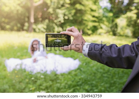 Beautiful young wedding couple taking pictures in a park