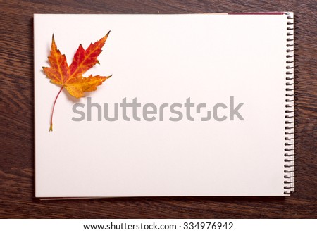 Autumn maple leaf on a notepad, space for your text