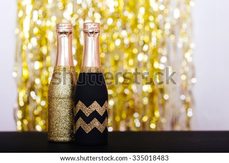Decorative sparkly champagne bottles with serpentine on light background