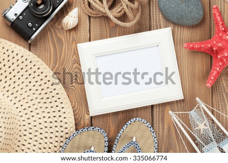 Travel and vacation photo frame and items on wooden table. Top view