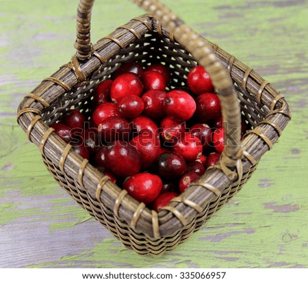 A basket of Cranberries on green wooden textured background, selective focus.