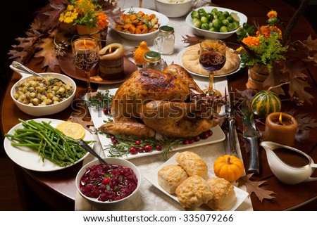 Roasted turkey garnished with cranberries on a rustic style table decoraded with pumpkins, gourds, asparagus, brussel sprouts, baked vegetables, pie, flowers, and candles.
 Royalty-Free Stock Photo #335079266