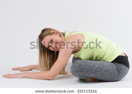 Blond woman doing yoga and stretching exercises, isolated on white