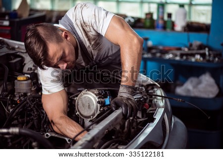 Picture showing muscular car service worker repairing vehicle