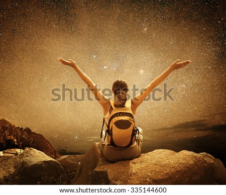 Hiker sit on top of a mountain and enjoying night sky view with a lots of stars. Picture of a series of Adventure and Travel.