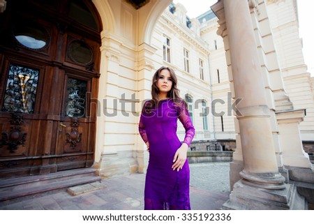 Young girl posing in a blue dress for the camera on a background of brown wooden door column with copy space for your text message or content, confident stylish woman looks to the side 