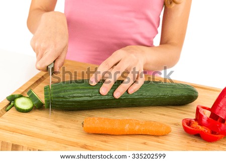 Woman cutting cucumber for salad