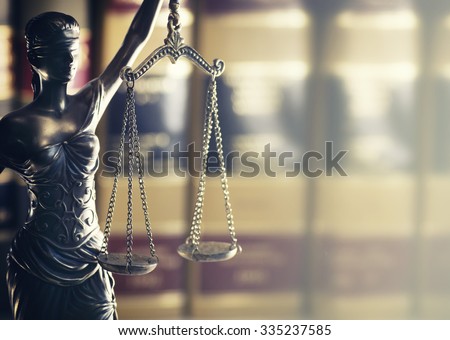 Burden of proof - Moodily lit legal law concept image with Scales of justice backlit and row of law books in background.  Hazy light from right good for text copy.