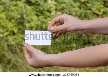 women's hands with card on the grass background