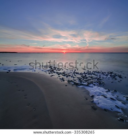 Sunset on the stone coast. Sea stones at sunset. Stones in water at sea during sunrise. Colorful sunset over the sea