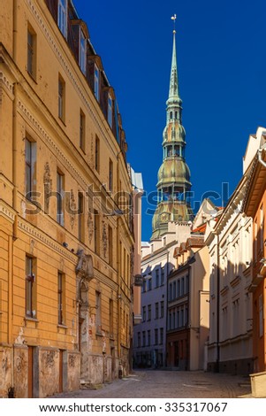 Narrow street of Old Town on a sunny day, Saint Peter church on the background, Riga, Latvia
