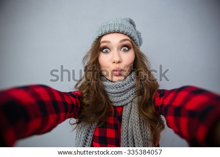 Portrait of a charming young woman making selfie photo over gray background