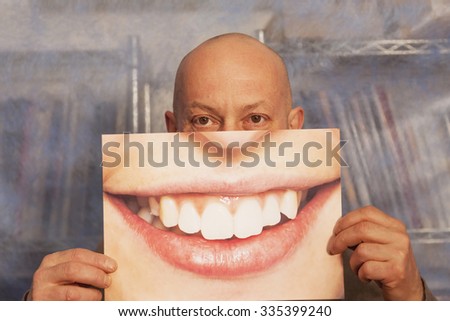bald man holding a card with a big smile on it