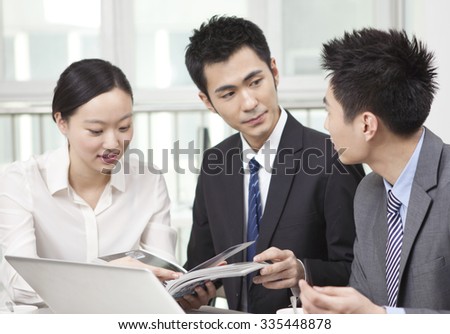 Group of businesspeople discussing with a magazine in office