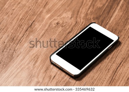 Smartphone on office teak wood table background.