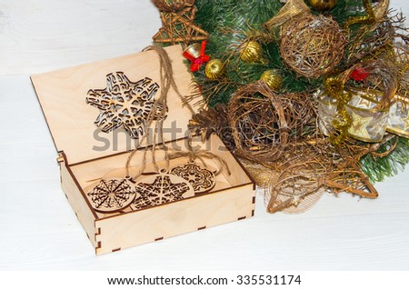 Christmas composition with snowflakes in box carved with out of wood and decorated with stars, a ball on a branch of a coniferous tree