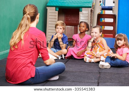 Discussion group of children in kindergarten talking to nursery teacher Royalty-Free Stock Photo #335541383