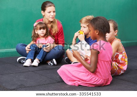 African girl reading aloud for group of children in a kindergarten