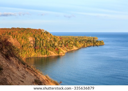 Au Sable Point in the upper peninsula of Michigan. Sunrise illuminates autumn foliage surrounding the Lighthouse with Lake Superior in the background.