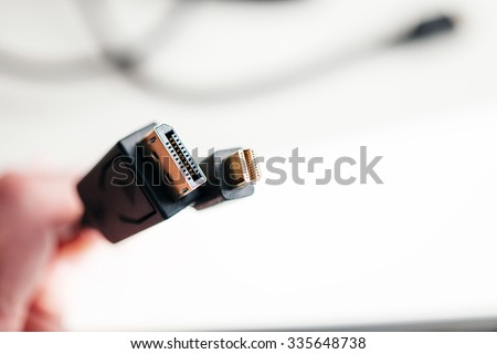 Hand holding Mini DisplayPort and DisplayPort cables with main focus to the cable connections - tilt-shift lens used