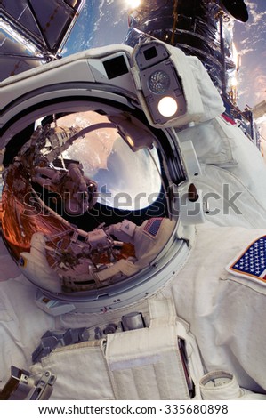 Selfie photo of astronaut spaceman in outer space with people on planet earth moonon on space mission. Warm color filter. Elements of this image furnished by NASA.