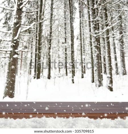 Blurred winter background with snow covered forest and shabby table