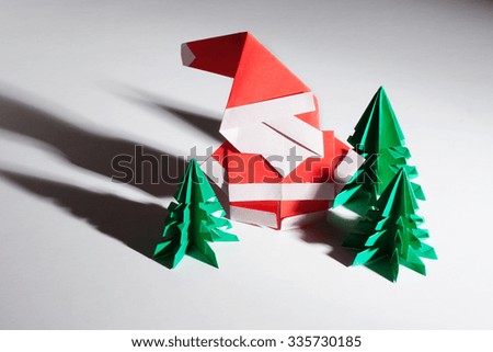 Origami santa claus with red and green trees isolated on white background.