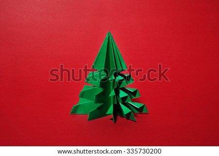 Christmas tree origami on red background.