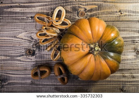 Photo top distant view closeup rustic autumn still life big whole fresh orange pumpkin with bunches of hard oval cracknels bind with string on wooden table on timber background, horizontal picture 